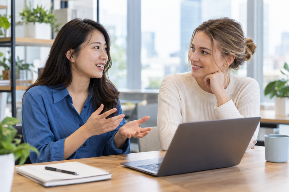 明るいオフィスで会話する二人の女性のイメージ
