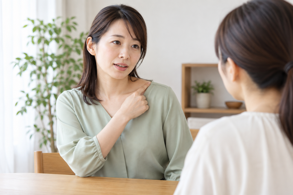 肩の上のつらい場所を指し示して説明する女性のイメージ