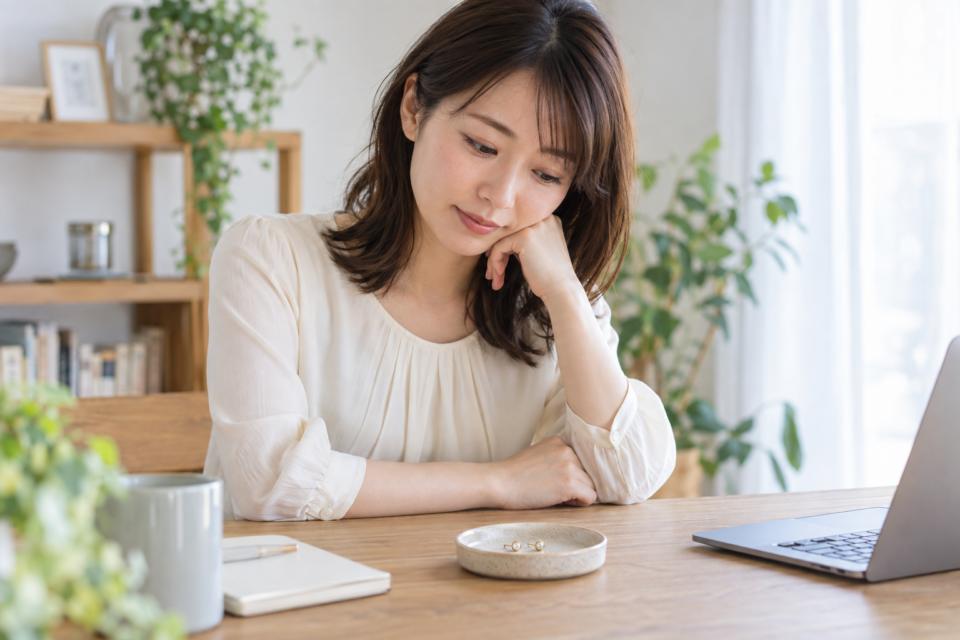 机の上のピアスを見ながら考える女性