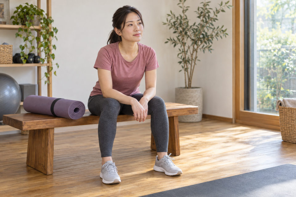 ベンチに座り運動前の肩の状態を確認する女性