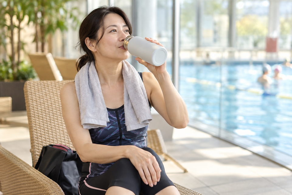 水中運動後に休憩場所で水分を取る女性