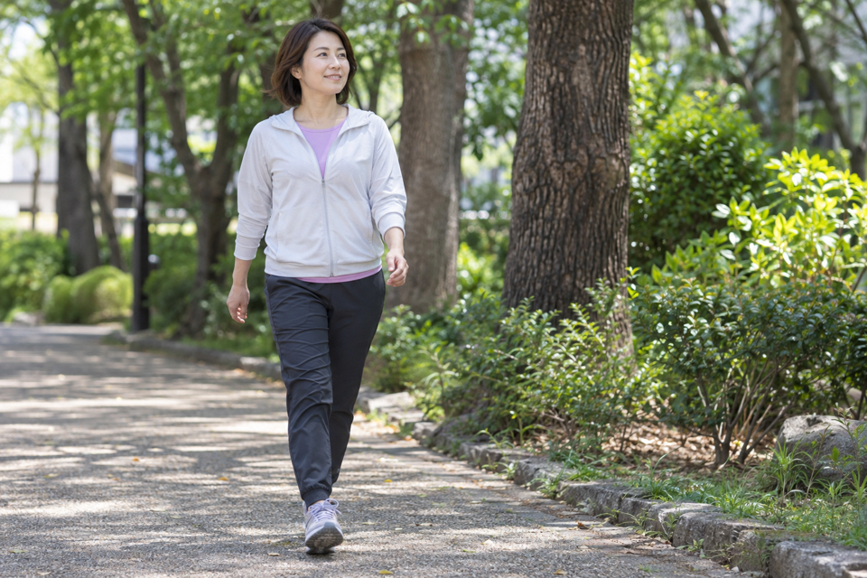 肩の力を抜いて公園の平らな道を歩く女性
