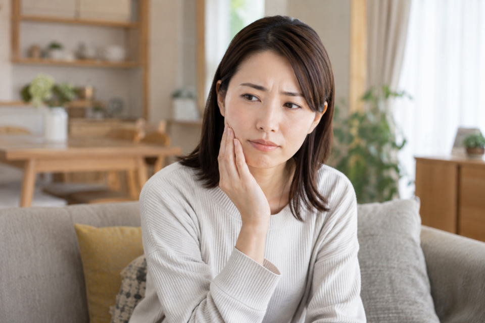 歯の痛みで頬に手を添える女性（AI生成イメージ）