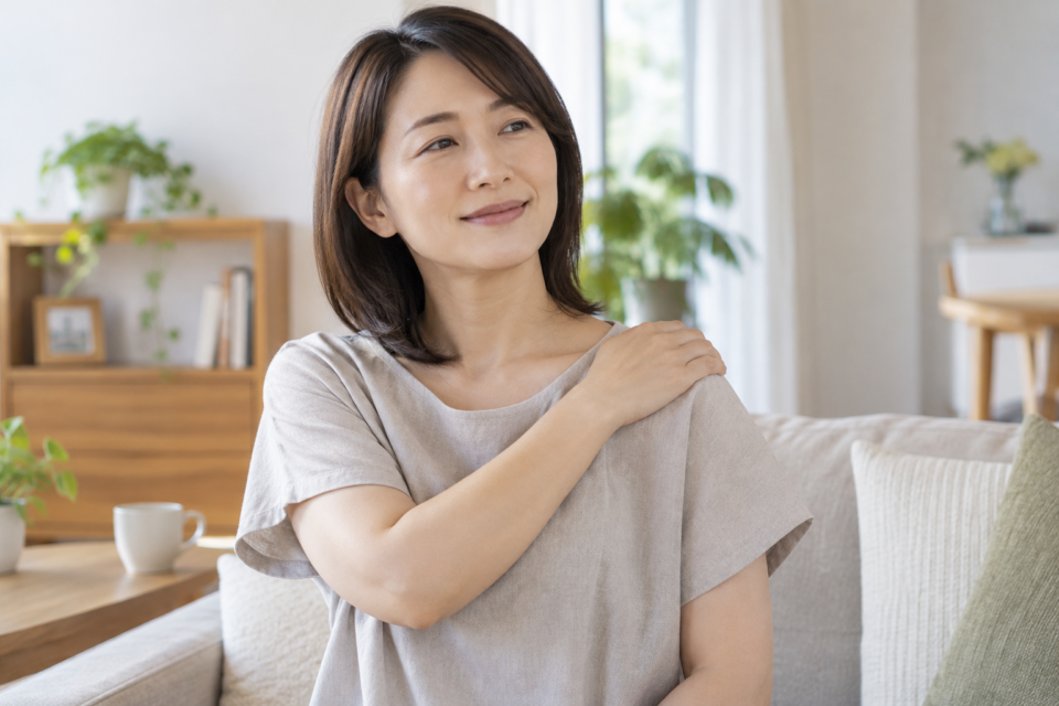 肩の上部に手のひらを軽く当てる女性(AI生成イメージ)