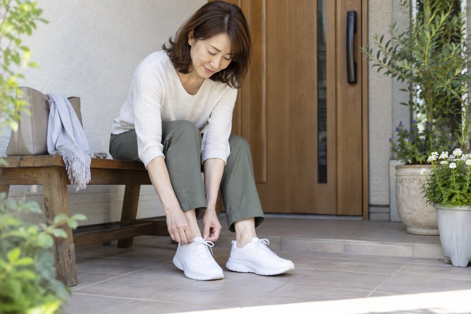 椅子に座り、足元のスニーカーのひもを調整する女性