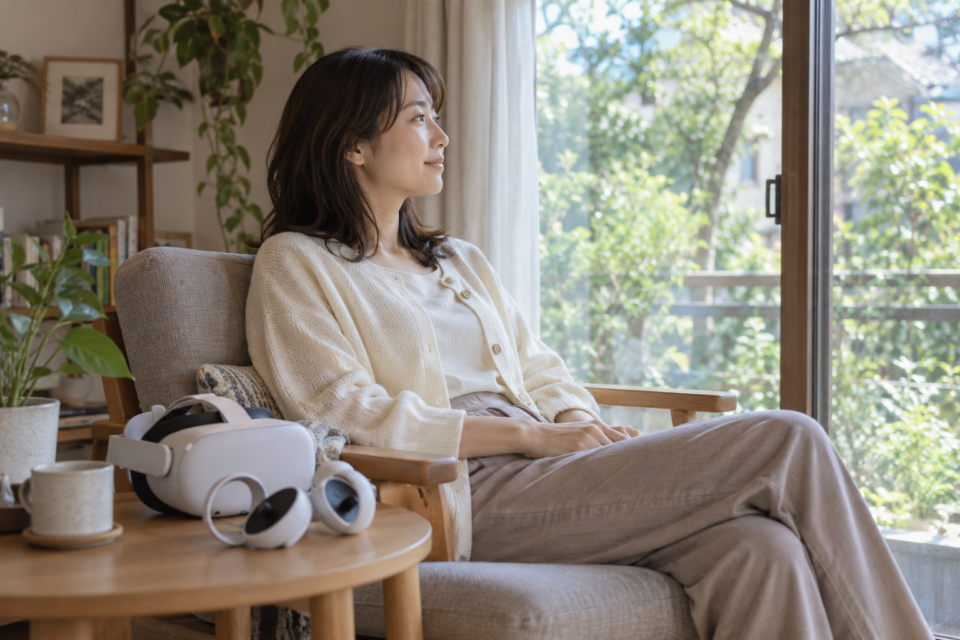 VR機器をテーブルに置き、窓の外を見ながら休憩する女性