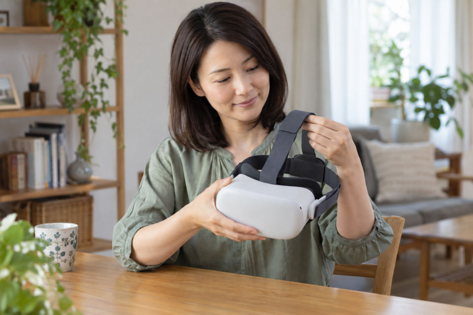 VRヘッドセットを外した状態でストラップを確認する女性