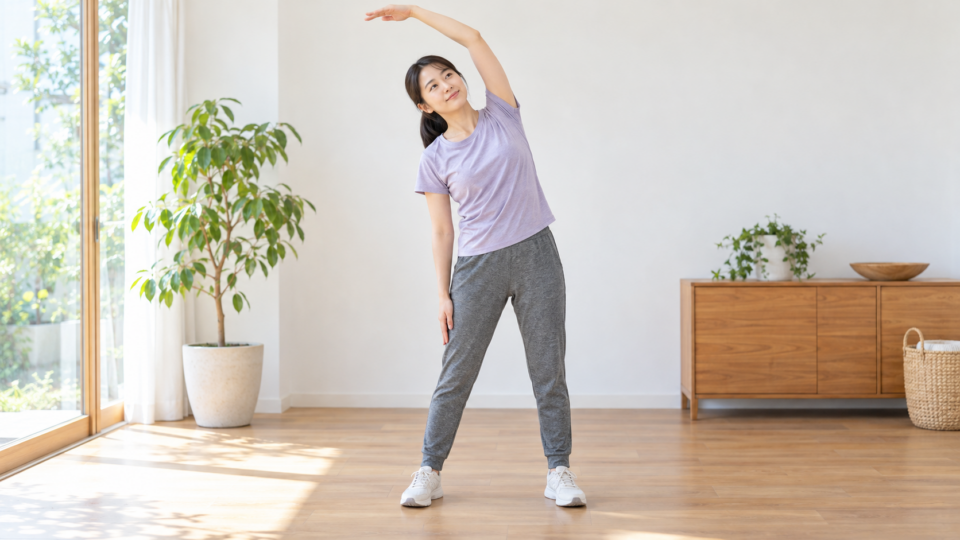片腕を上げ、体を横へ穏やかに傾ける女性