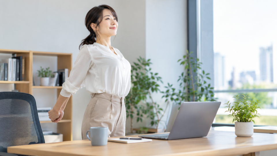 デスク作業の合間に立ち上がる女性のAI生成イメージ