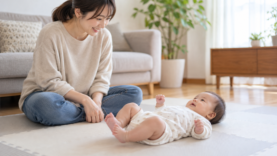 保護者が見守る平らなマットの上で脚を自然に動かす赤ちゃんの説明用AI生成画像
