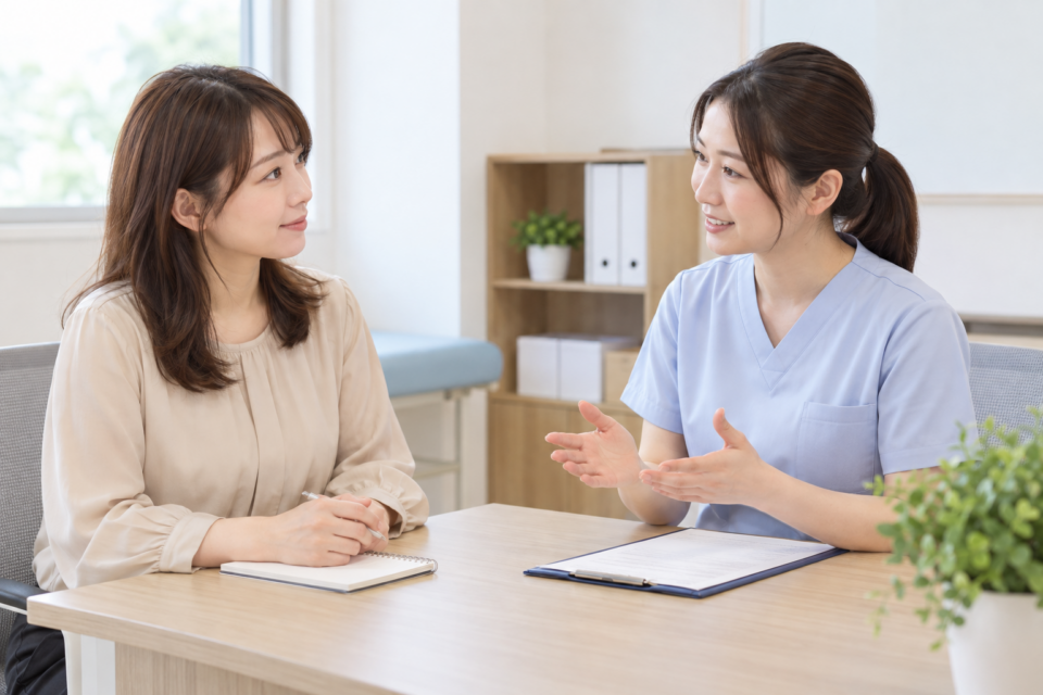 着衣のまま医療スタッフへ肩の症状を相談する女性