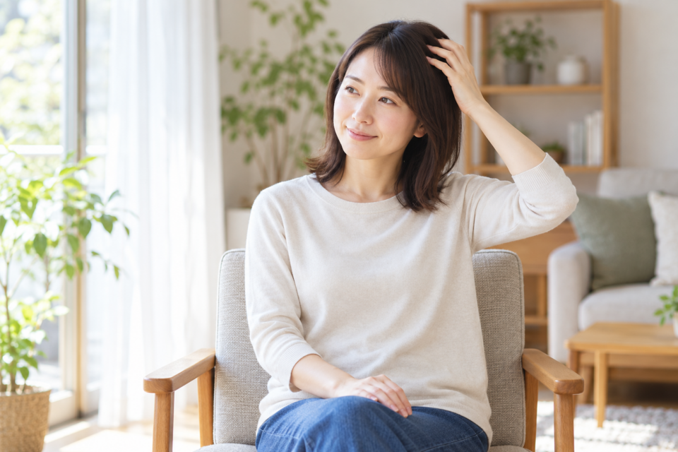 こめかみ近くの髪に軽く手を添える女性